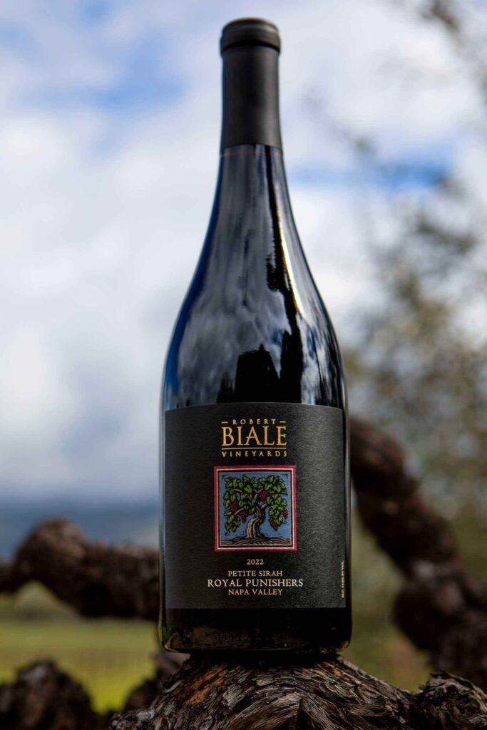 Bottle of Biale Royal Punishers Petite Sirah perched on the knot of a gnarled vine