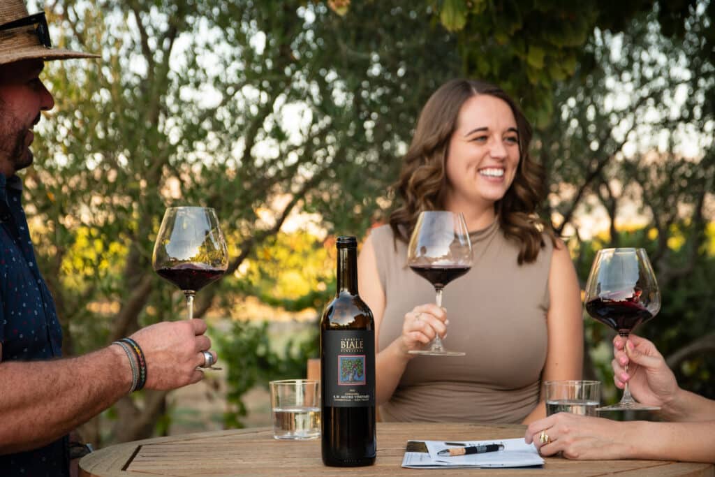 friends gather around a table holding glasses of R.W. Moore Vineyard zinfandel