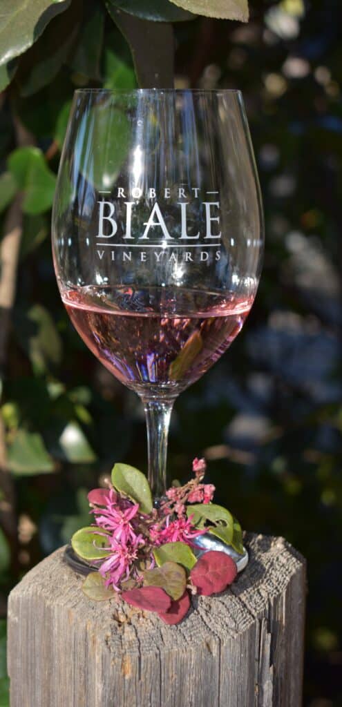 a glass of Biale Rosato in a logo glass with small florals at the base of the glass